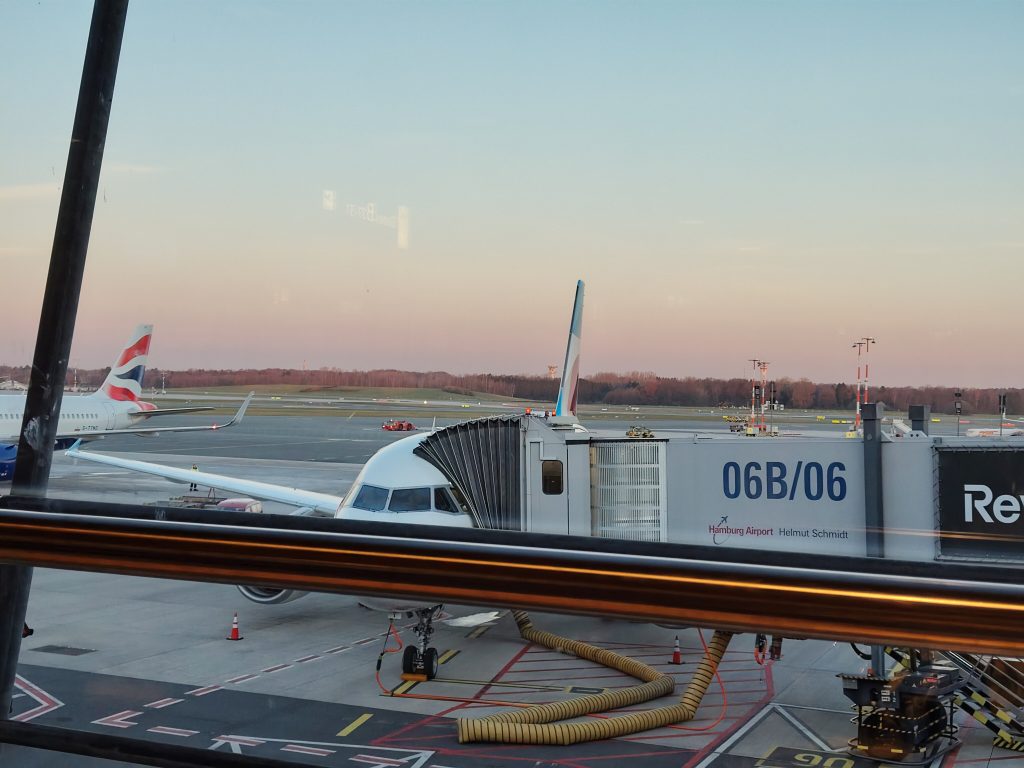 Foto: Flugzeug bereit zum Boarding am Hamburger Flughafen, im Hintergrund der Sonnenaufgang.