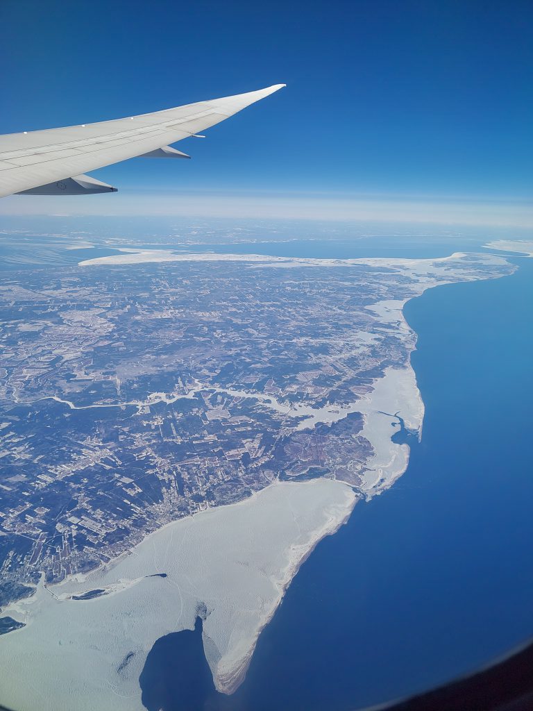 Foto aus dem Flugzeug heraus auf Kanadas Ostküste mit Blick auf Meer und das verschneite Ufer.