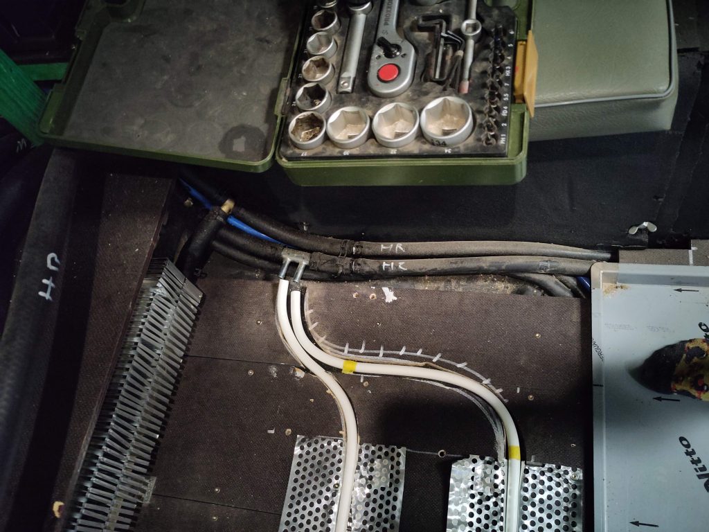 Bild 3. Anschlussfußbodenheizung an Warmwasserschlauch. Der Doppeladapter passt nicht und wurde später durch Baumarkt-Bedarf getauscht. Der Adapter ist für die "Alde Fußbodenheizungsmatten". Die schwarzen Schläuche sind der Heizungszulauf (HZ) und Heizungsrücklauf (HR). Links im Bild kann man erahnen, dass der Zulauf in den oberen Konvektor geht und der Rücklauf in den unteren.