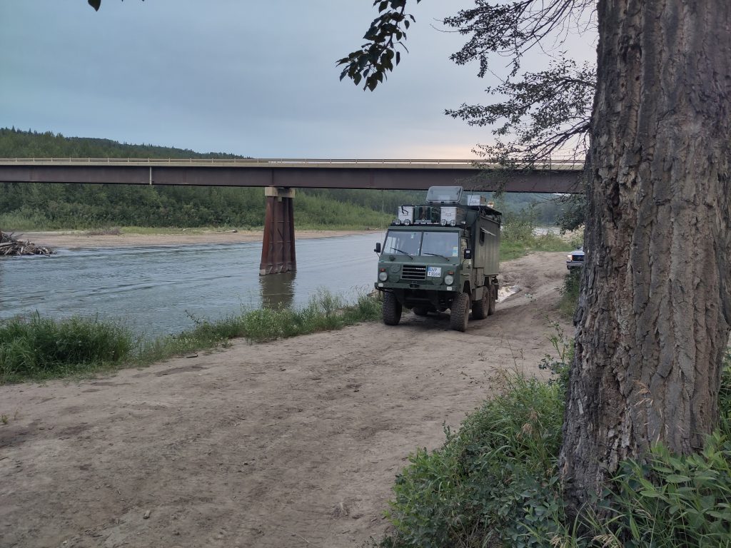 Volvo am Fluss mit Brücke im Hintergrund