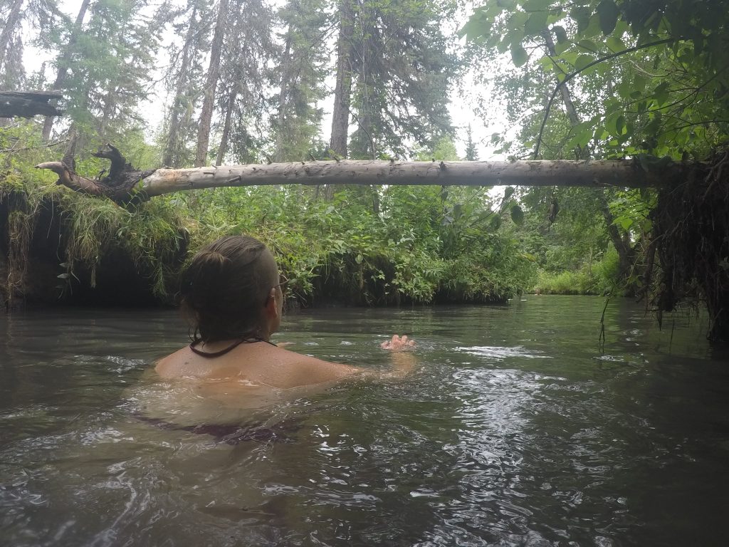 Bretti schwimmt zurück zum warmen Teil umgeben von Wald