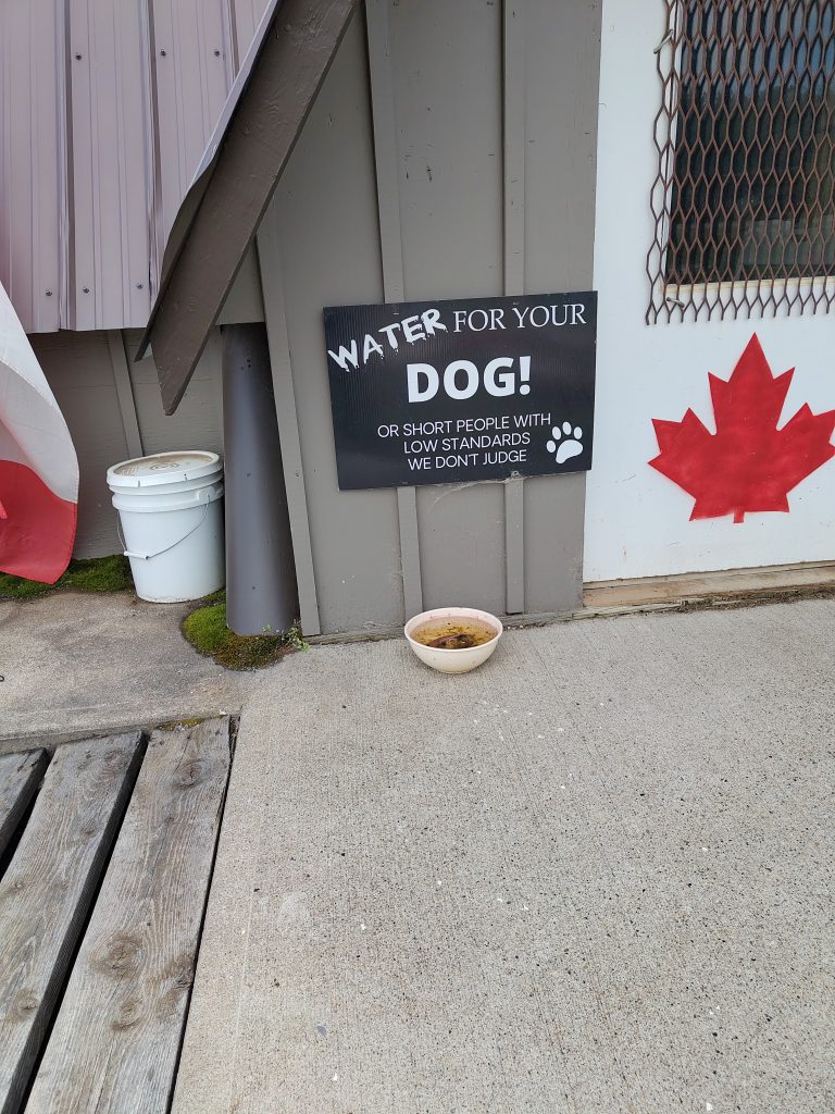 Schild an der Hundetränke: Wasser für die Hunde oder kleine Leute mit niedrigen Standards. Wir verurteilen nicht.